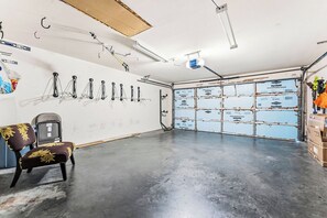 Eine Garage mit Betonboden, einem Stuhl, Haken an der Wand und einer isolierten Garagentür.