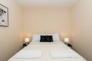 A hotel room with a bed, two bedside lamps, a framed picture on the wall, and a white headboard. - Toast Stays - The Langley Nook (Hill Top)