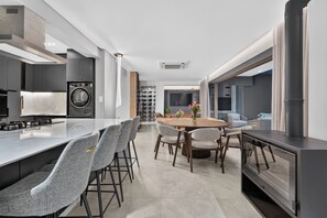Una cocina moderna con una isla central, electrodomésticos integrados y un comedor con una mesa redonda y sillas.
