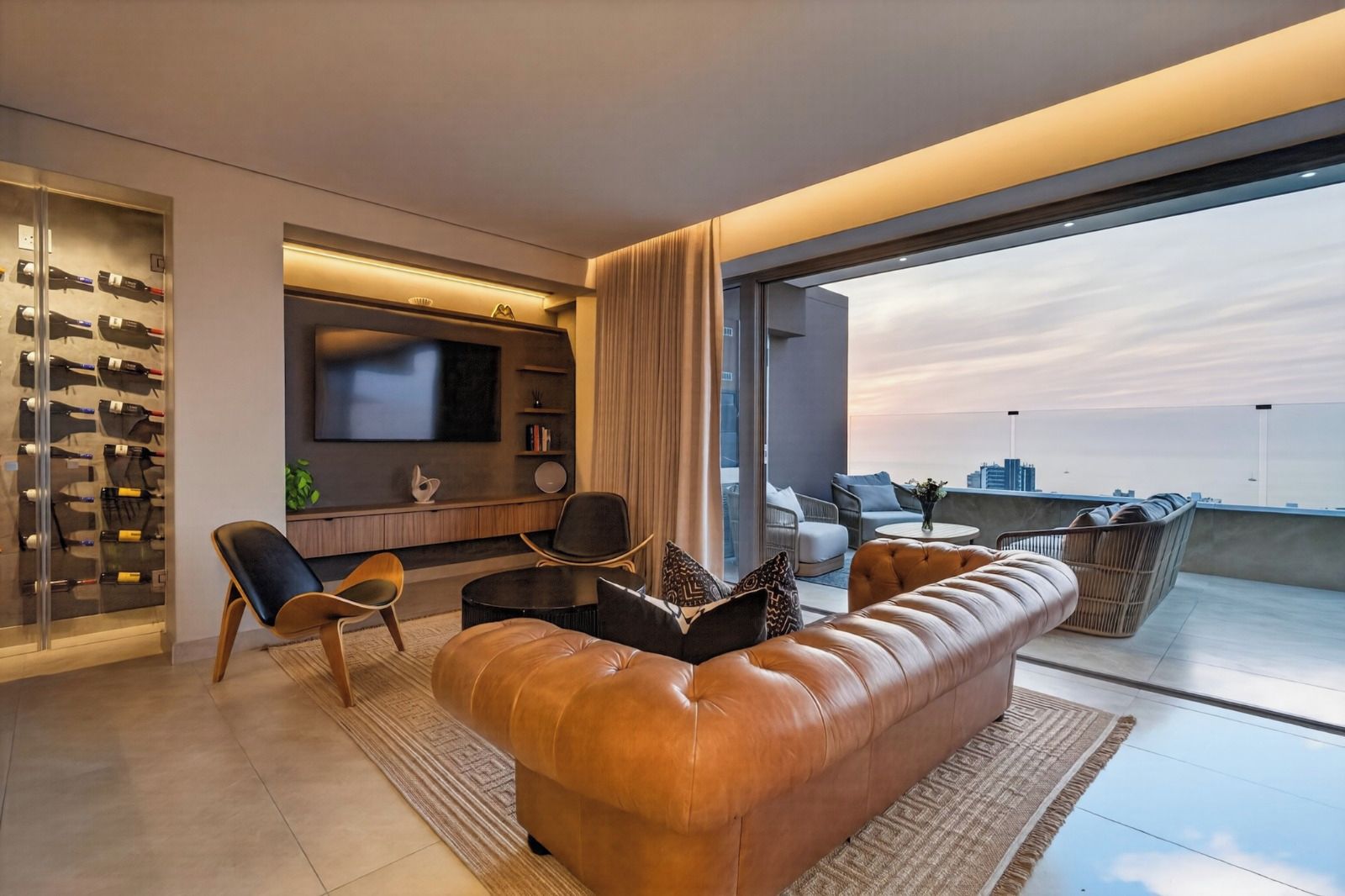 A modern living room with a leather sofa, a flat-screen TV, and a wine rack.