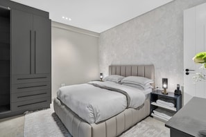 Un dormitorio moderno con cama, mesitas de noche, un armario y una mesilla.