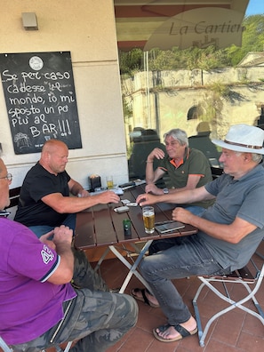A group of people seated at an outdoor table with a chalkboard menu, a bottle of beer, and a smartphone on the table. - countryside villa with pool quads next near beach mountains rome naples by train (Lazio)