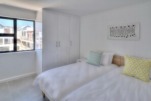 Una camera da letto con un letto, due cuscini, un comodino, un armadio e una finestra vista edifici.