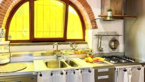 A kitchen with a large arched window, stainless steel appliances, and a gas stove. - La Cicala (Rosignano Marittimo)