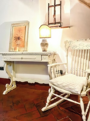 A white rocking chair with a cushioned seat and back, positioned next to a white desk with a lamp and a framed picture. - La Cicala (Rosignano Marittimo)