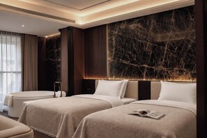 Una habitación de hotel con dos camas, una gran pared de mármol y un diseño moderno.