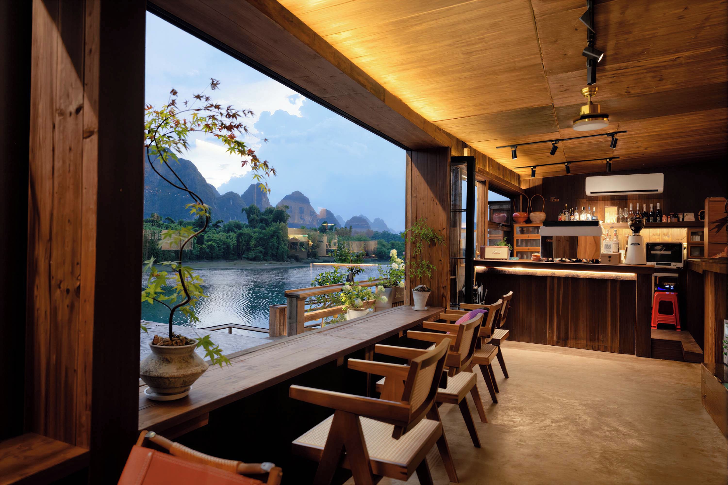 Un interior de madera con comedor que da a un río y montañas.