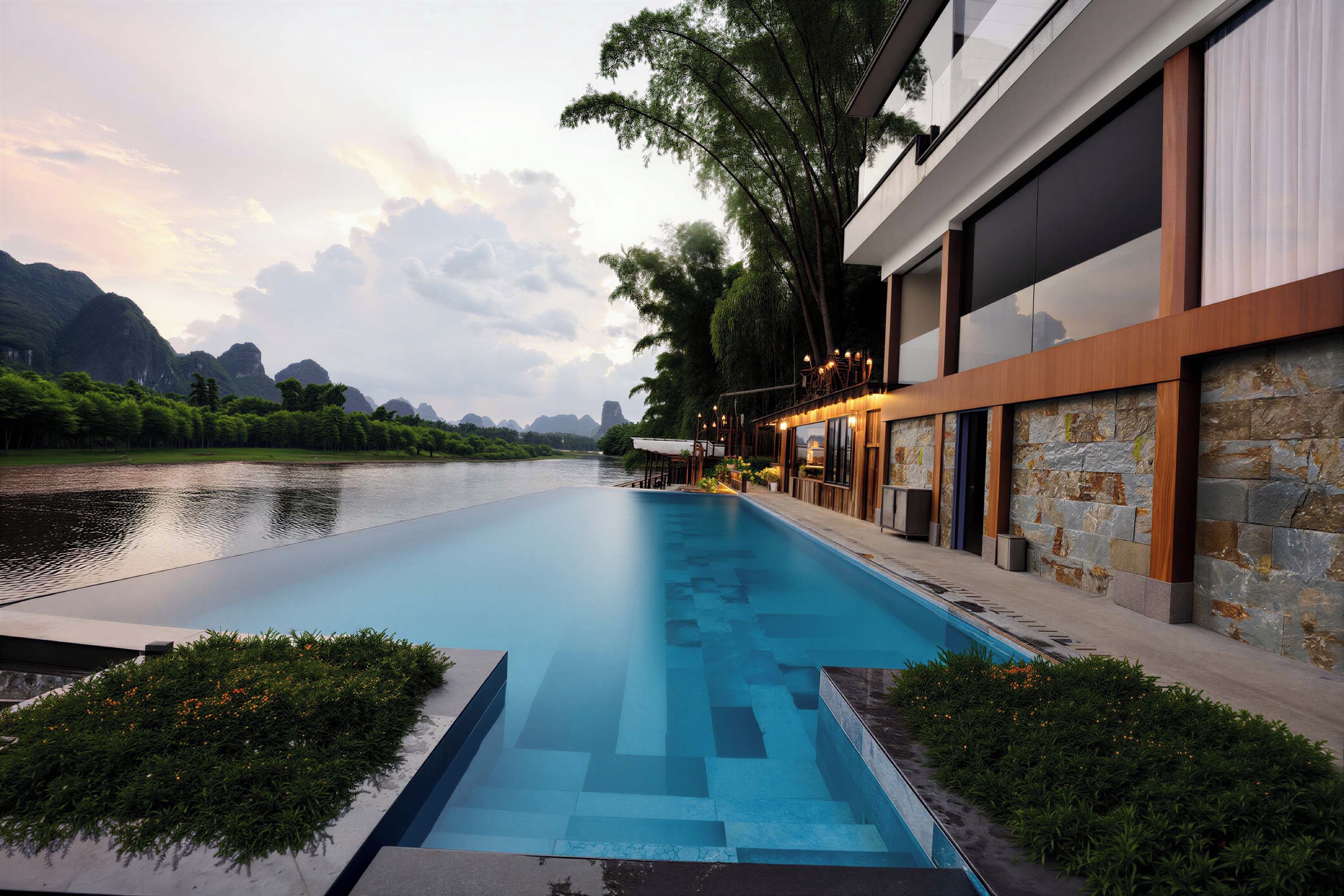 A modern hotel with a swimming pool, stone walls, and a view of a river and mountains.