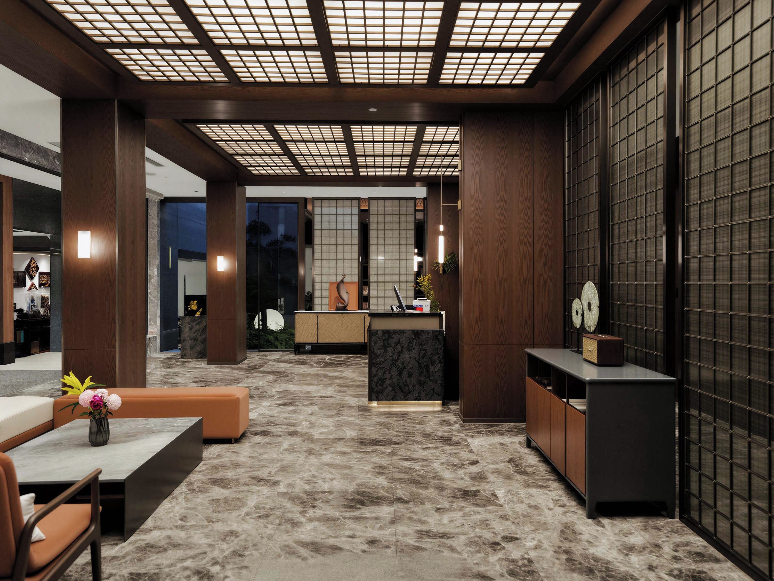 A modern lobby with a reception desk, seating area, and a patterned floor.