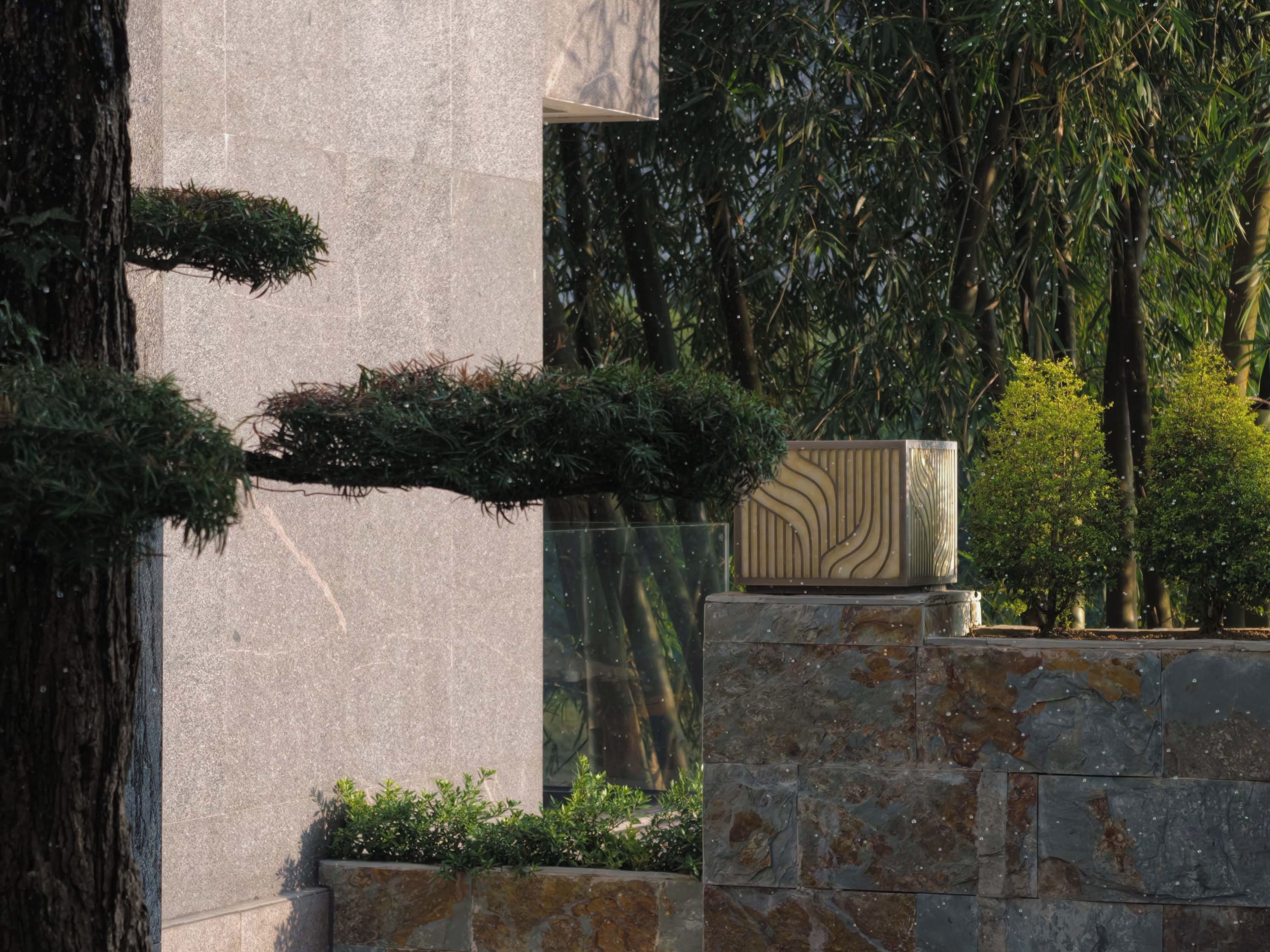 A stone wall with a geometric patterned planter and a bonsai tree.