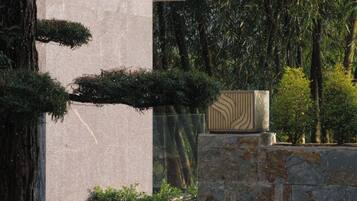 A stone wall with a geometric patterned planter and a bonsai tree.