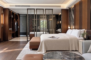A modern bedroom with a large bed, a nightstand, a seating area, and a walk-in closet. - Riverside Paradise Luxury Resort Villa (Guilin)