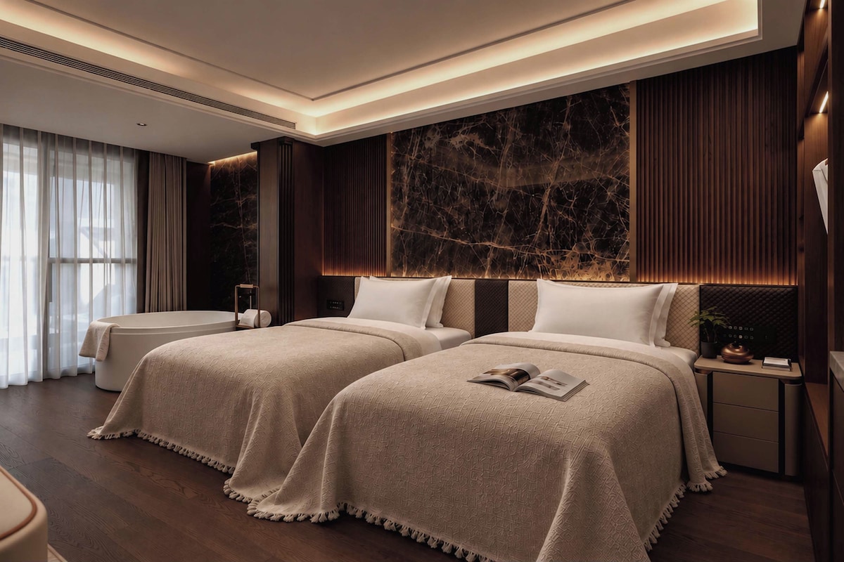 A modern hotel room with two beds, a large marble accent wall, and a view of the city through sheer curtains.