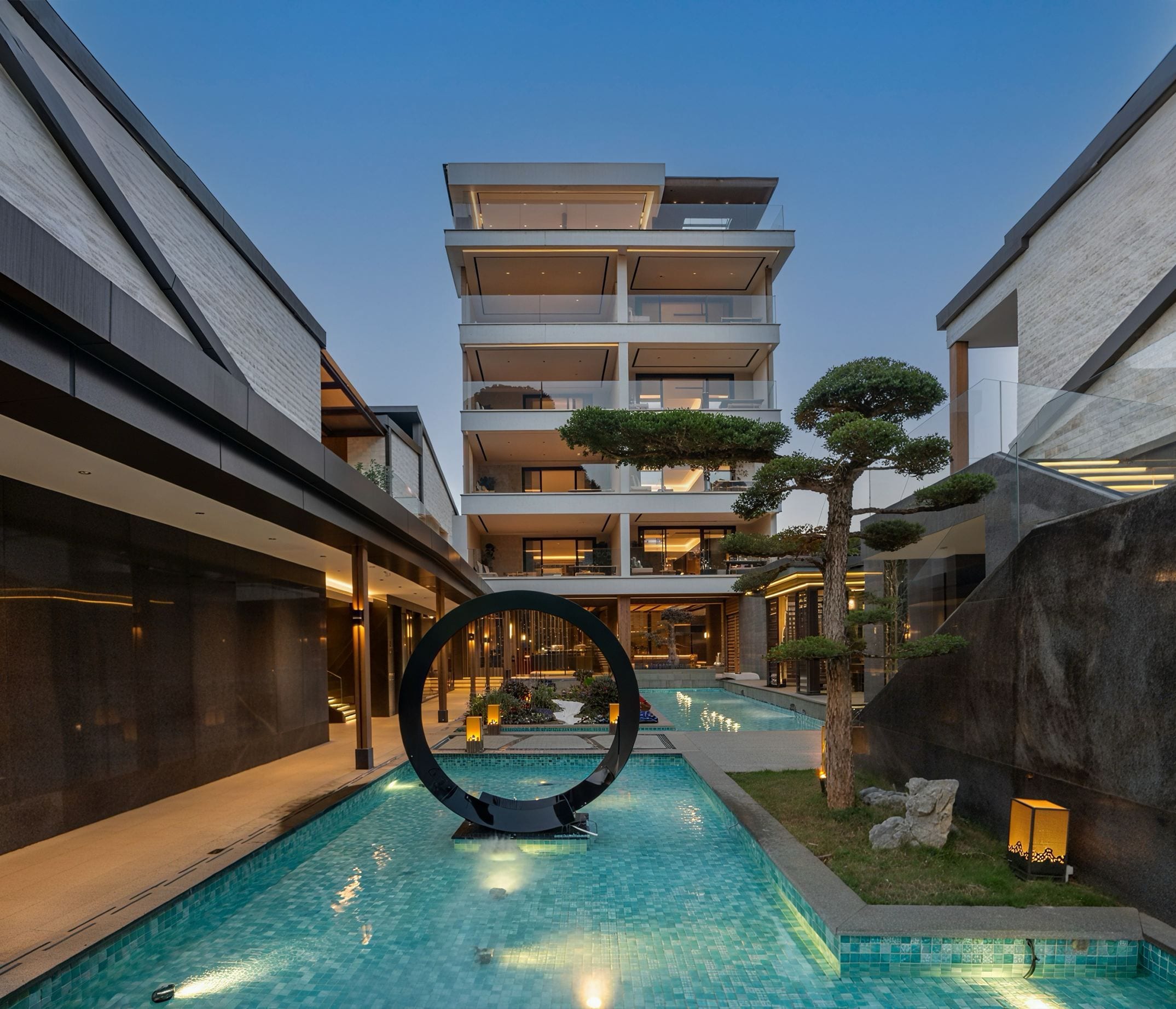 A modern hotel with a central pool, multiple floors, and a distinctive circular sculpture.