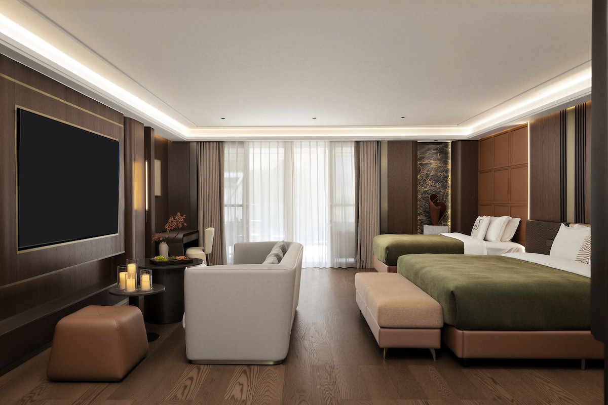 A modern hotel room with a flat-screen TV, a sofa, a bed, and a dining area.