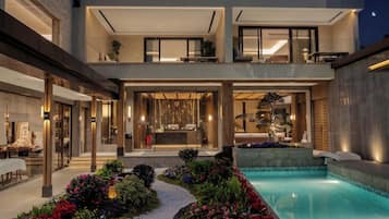 A modern two-story building with a swimming pool, outdoor seating, and a reception area.
