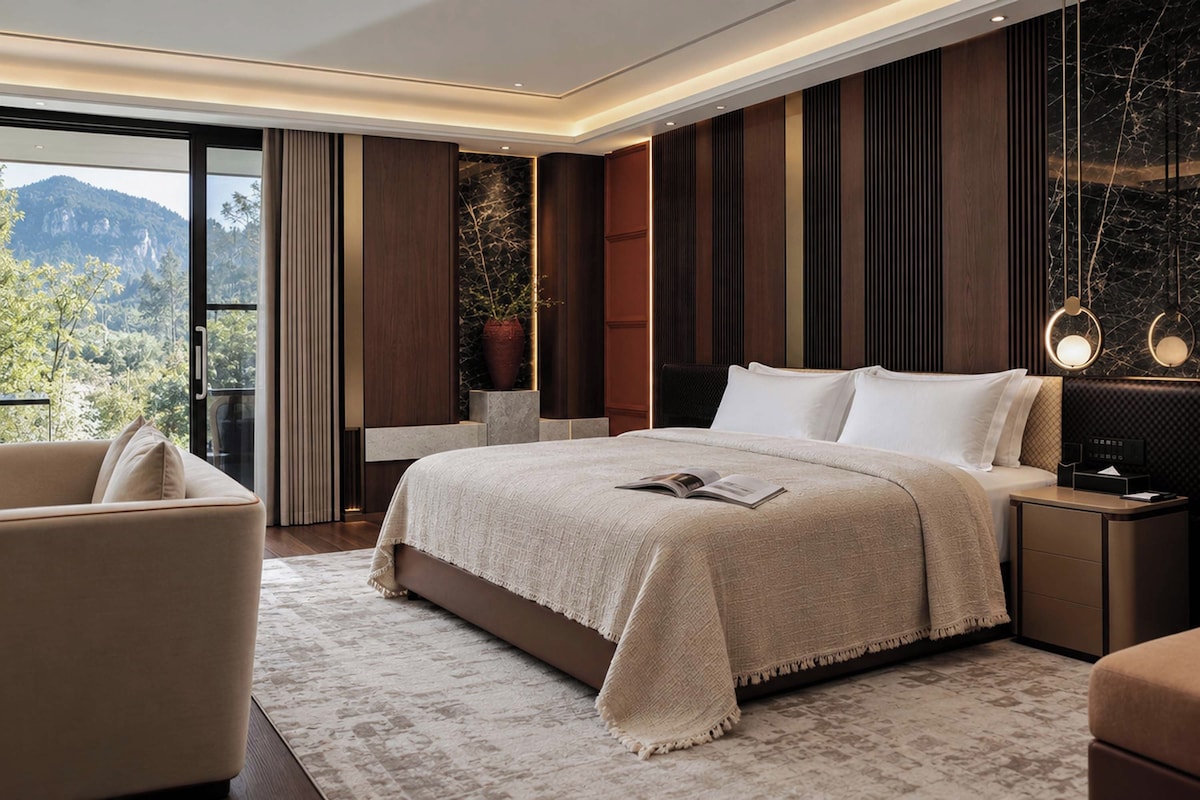 A modern bedroom with a large bed, a seating area, and a view of the outdoors.