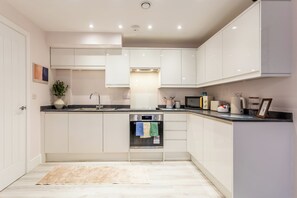 A modern kitchen with white cabinetry, a built-in oven, and a microwave. - Toast Stays - The Bluebell at Parsons House (Washington)