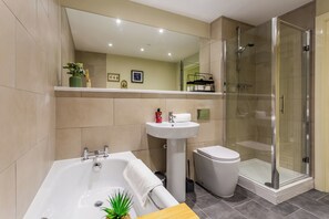 A modern bathroom with a bathtub, sink, toilet, and glass-enclosed shower. - Toast Stays - The Bluebell at Parsons House (Washington)