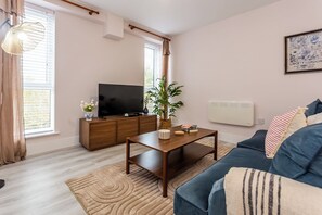 A living room with a television, a wooden coffee table, a blue sofa, and a potted plant. - Toast Stays - The Bluebell at Parsons House (Washington)