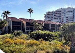 A multi-story building with balconies, surrounded by lush greenery and palm trees. - 2-bedroom condo in serene Marco Island right on the beach (Marco Island)