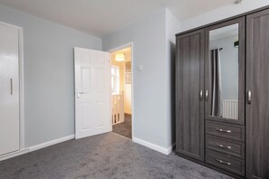 A room with a white door, a dark wooden wardrobe, and a carpeted floor. - Toast Stays - Larchcroft (Shildon)