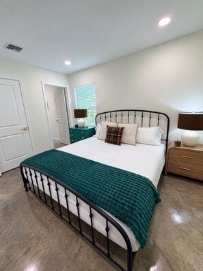 A bedroom with a bed, bedside tables, and a door. - Frenchman Inn-KING-WiFi-Near ULL/Downtown/Sports (Lafayette)