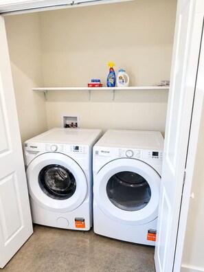 Ein Waschraum mit zwei Whirlpool Waschmaschinen und einem darüberliegenden Regal für Reinigungsmittel.
