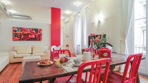 A dining area with a wooden table, red chairs, a red kettle, and a painting on the wall. - Italianway Comfort - Agudio 8 (Milano)