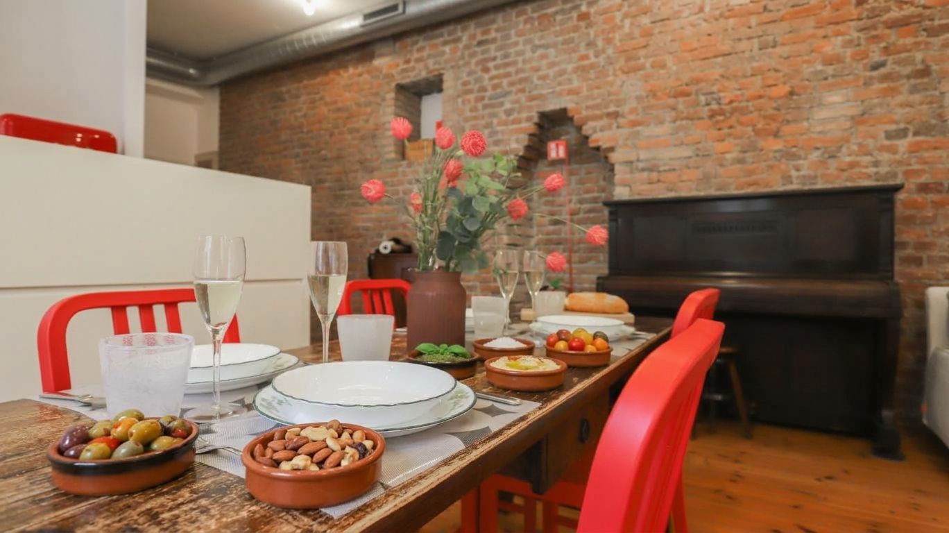 A dining area with a brick wall, a fireplace, and red chairs.