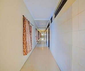 Un largo pasillo de hotel, con cortinas estampadas en un lado y paredes lisas en el otro.