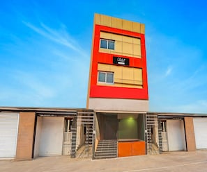Ein mehrstöckiges Gebäude mit roter und beiger Fassade, einer Schrifttafel mit der Aufschrift 'Collection & Company Services' und einer Treppe, die zum Eingang führt.