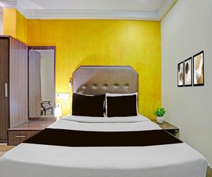 A hotel room with a bed, a bedside table with a plant, and a mirror. - Classic Vijaya Raghava Residency (Machilipatnam)