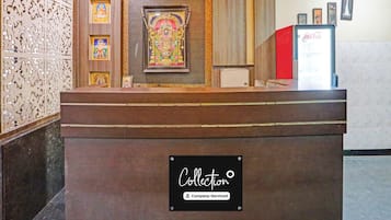 A reception desk with a 'RECEPTION' sign, framed religious artwork, and a 'Collection' sign indicating company service.