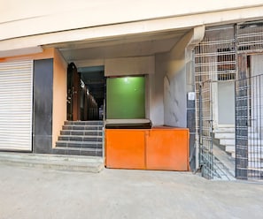 Une entrée d’immeuble avec une porte verte, un escalier et un portail en métal.