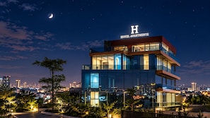 Un moderno edificio de hotel con un llamativo letrero con la letra 'H', varios pisos y amplias ventanas.