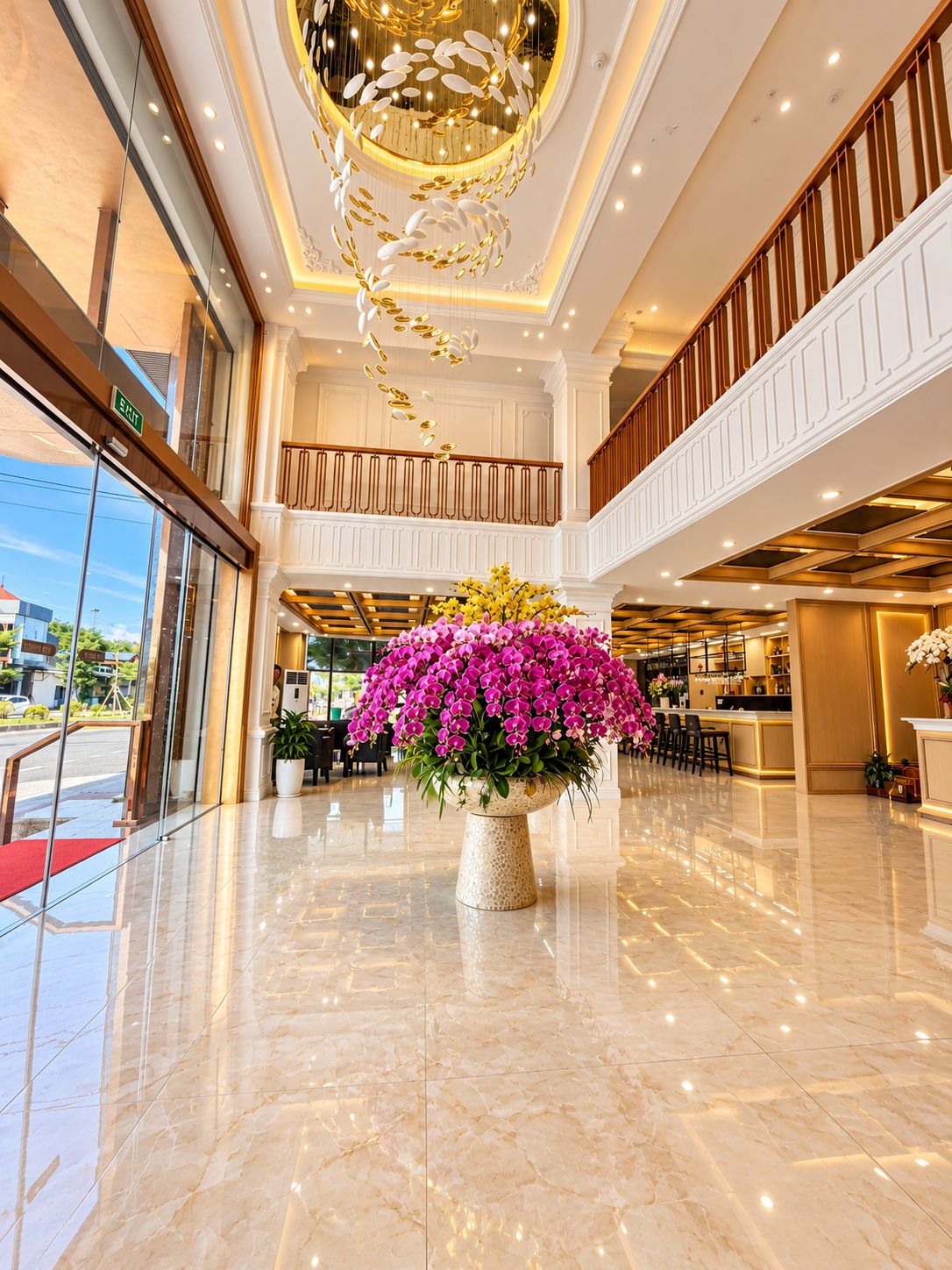 A hotel lobby with a marble floor, a large floral centerpiece, and a modern chandelier.