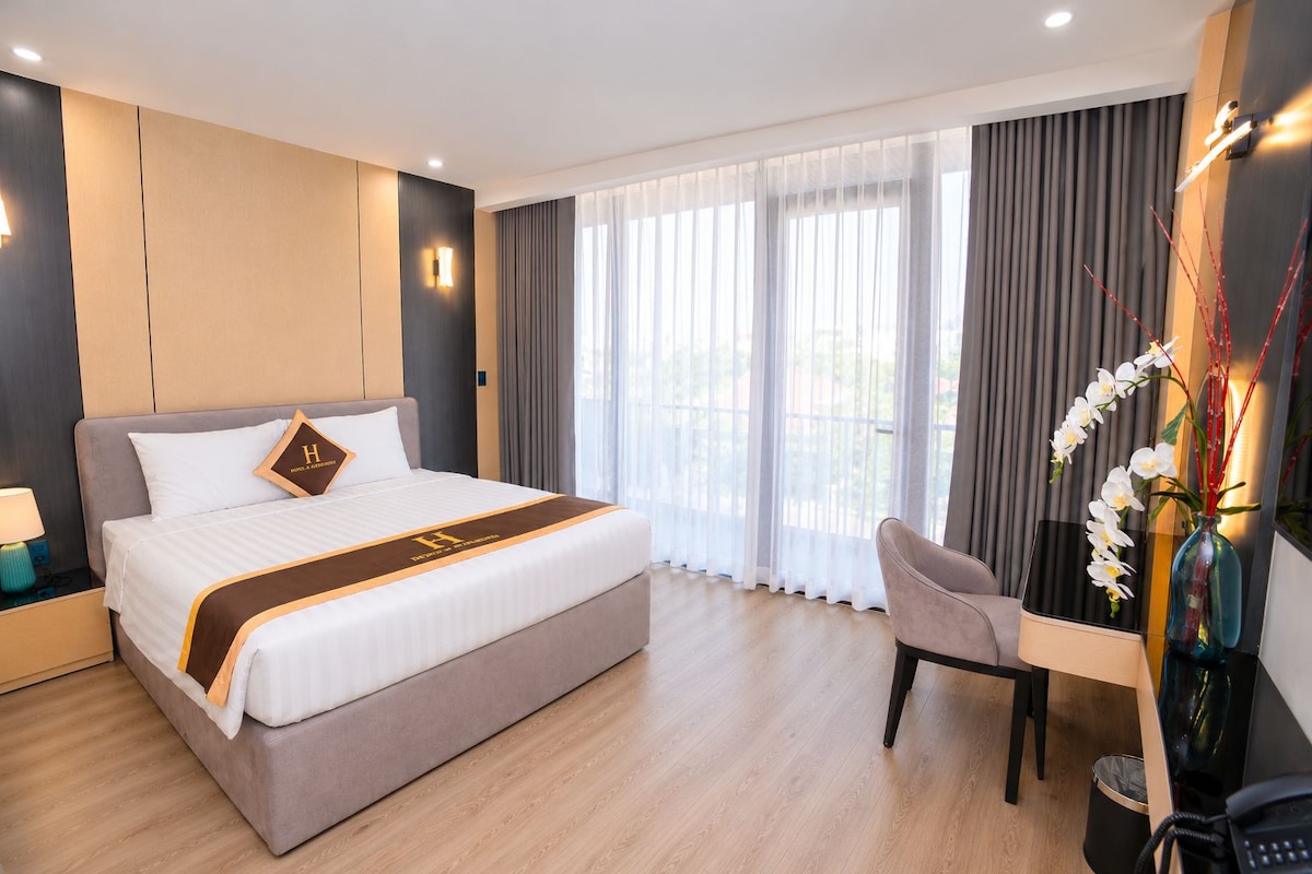 Una habitación de hotel con una cama grande, un escritorio y una silla.