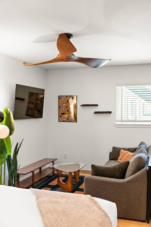 A modern living room with a ceiling fan, a sofa, a coffee table, and artwork on the walls. - Modern Stay Near Downtown Houston (Houston)