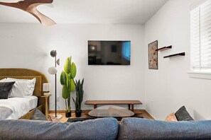 A modern bedroom with a bed, a bedside table, a floor lamp, a small table, and a potted plant. - Simple & Modern Stay in Houston (Houston)