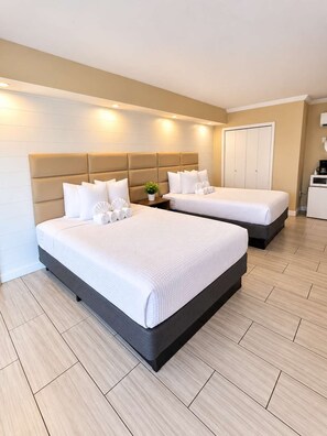 A hotel room with two beds, a bedside table with a plant, a wardrobe, and a coffee maker. - Good Tides at 300 Tenth | 101 (Myrtle Beach)