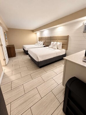 Ein Hotelzimmer mit zwei Betten, einem Schreibtisch und einem Mülleimer.