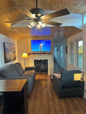 A cozy living room with a fireplace, a television, and a ceiling fan. - 34 acre Retreat Mountain View hiking trails King 1bedroom 23 mins to Cleveland (Calhoun)