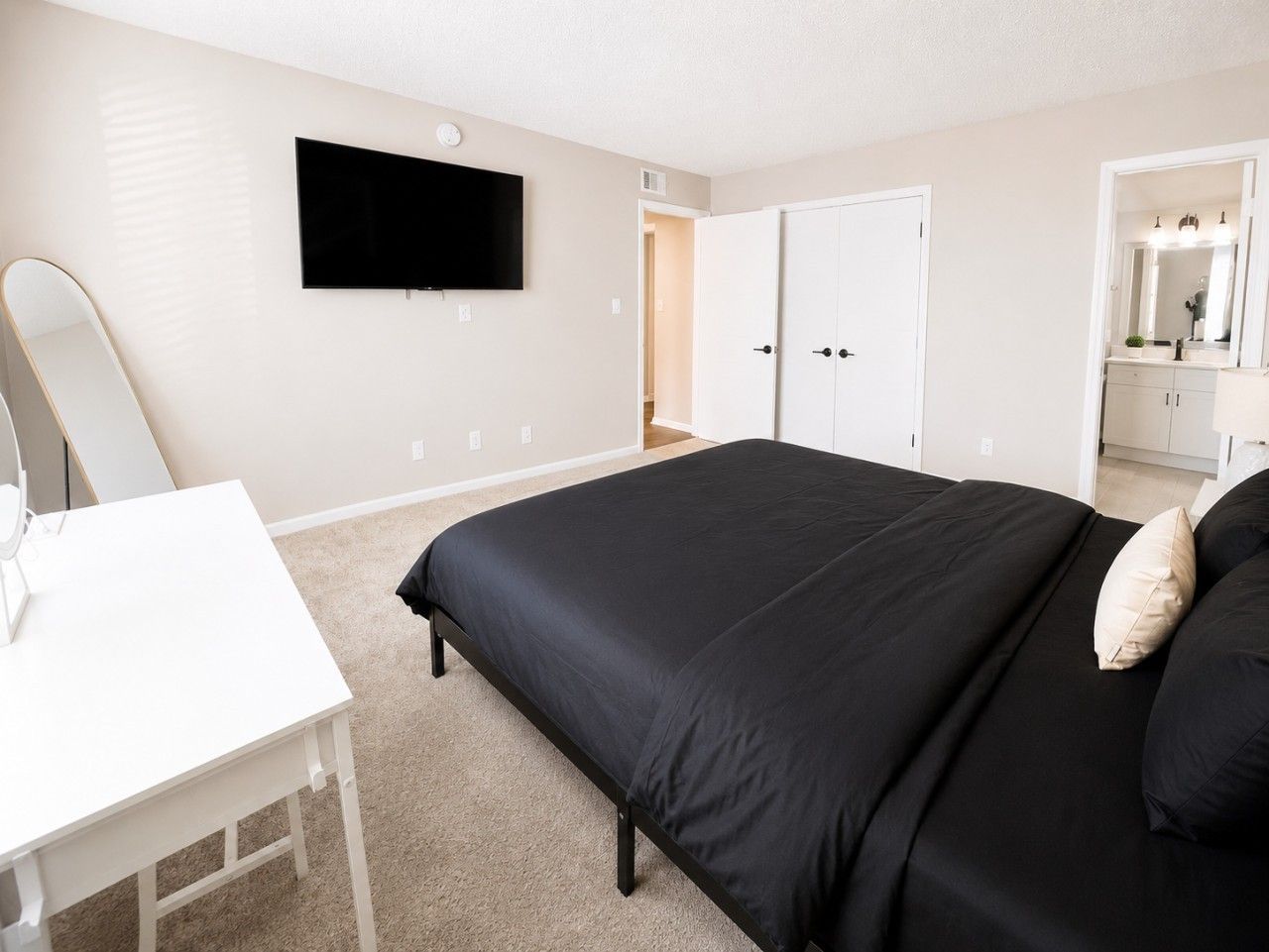 A bedroom with a bed, a desk, a television, and a wardrobe.