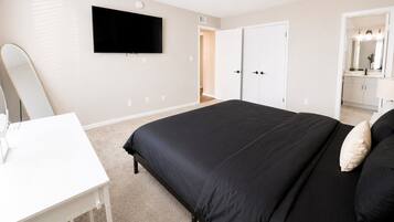 A bedroom with a bed, a desk, a television, and a wardrobe.
