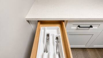 A kitchen drawer with a white interior and a wooden exterior.