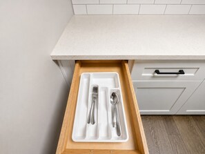A kitchen drawer with a white interior and a wooden exterior.