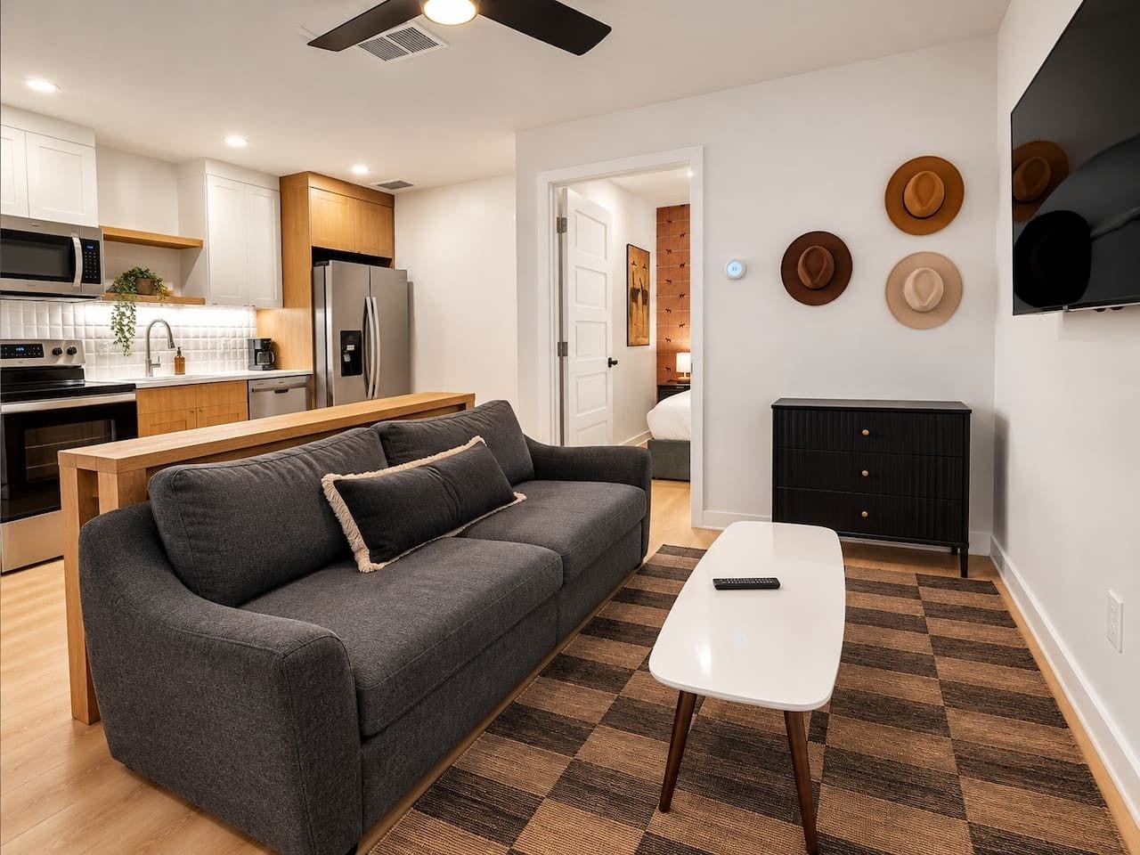 A modern living space with a sofa, a coffee table, a kitchen area, and a fireplace.