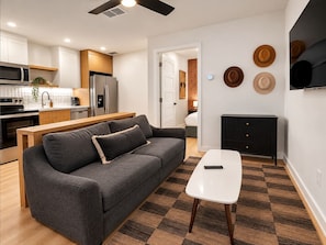 Ein moderner Wohnraum mit Sofa, Couchtisch, Küchenzeile und Kamin.