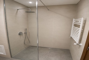 A glass-enclosed shower with a handheld showerhead, a wall-mounted towel rack, and a tiled floor. - Peaceful Garden (Tunis)